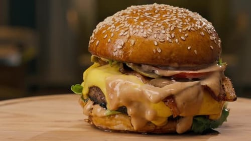 A close-up of a juicy burger with beef patty with vegetables and cheese cooked in the kitchen