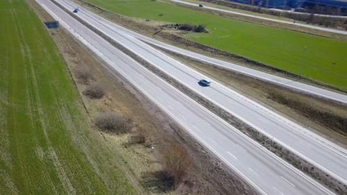 Freeway Road with Moving Cars Between Green Fields