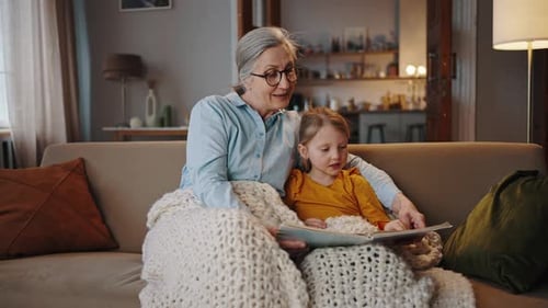Grandmother and Granddaughter Reading Storybook on Couch