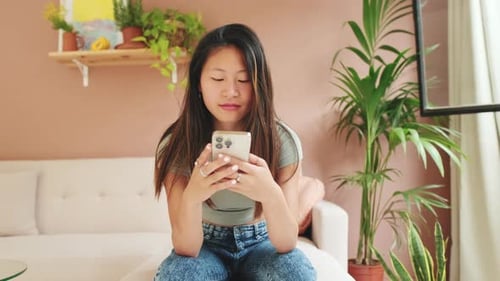 Woman Using Mobile Phone Relaxing at Home
