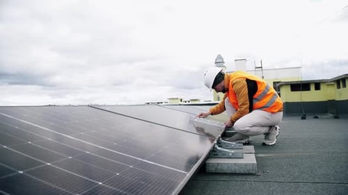 Man Installs Solar Panels on Building Roof