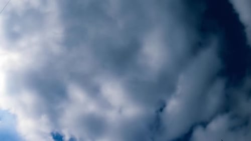 Deep blue sky hardly seen behind the quickly flying white clouds.