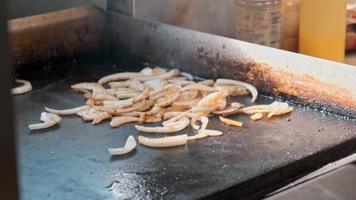 A close up 4k shot of caramalized onions being cooked on a hot flat stove top.