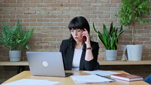 Woman Talking on Phone While Working at Desk