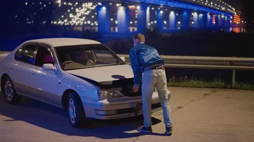 Man Fixing Vehicle at Night Beneath Vibrant Blue Bridge Lights Repair Expert Conducts Roadside Car