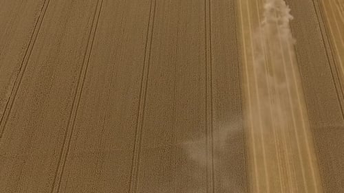 Harvest drone fly over field then pan up to reveal combine harvester working