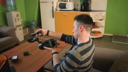 Man Setting Up Camera with Microphone in Home Studio Adjusting Equipment