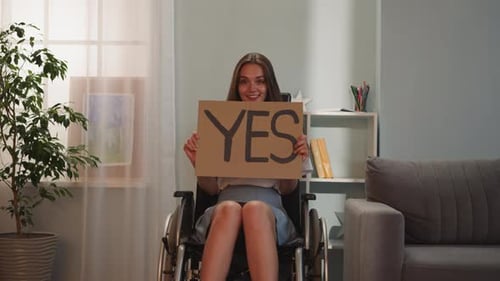 Smiling Woman in Wheelchair Holds "YES" Sign