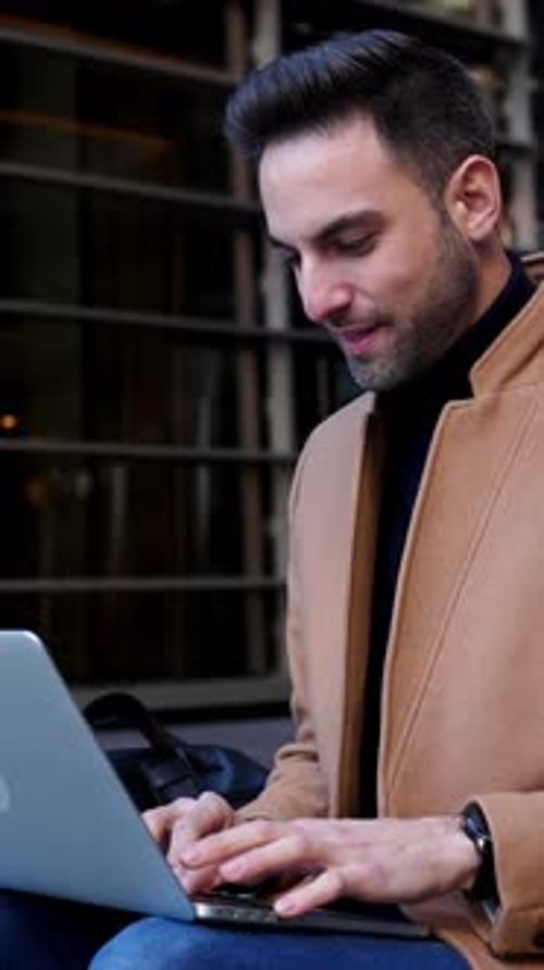 Businessman Working on Laptop Sitting at Office Building Entrance Stairs