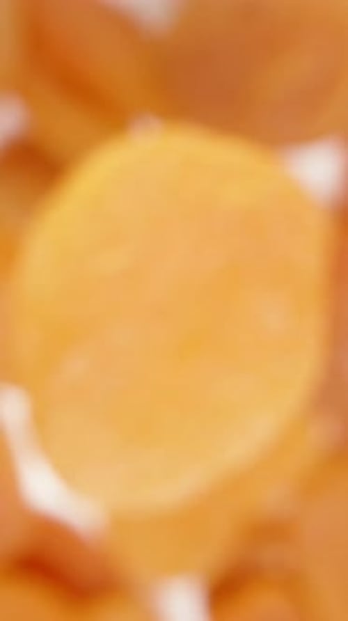 Vertical video. Top view of a pile of dried apricots. One is rotating on top of the others.
