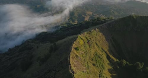 Mount Batur ridge with hiking trail visible during sunrise, aerial