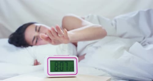 Woman Sleeping in Bed Turns Off Alarm Clock