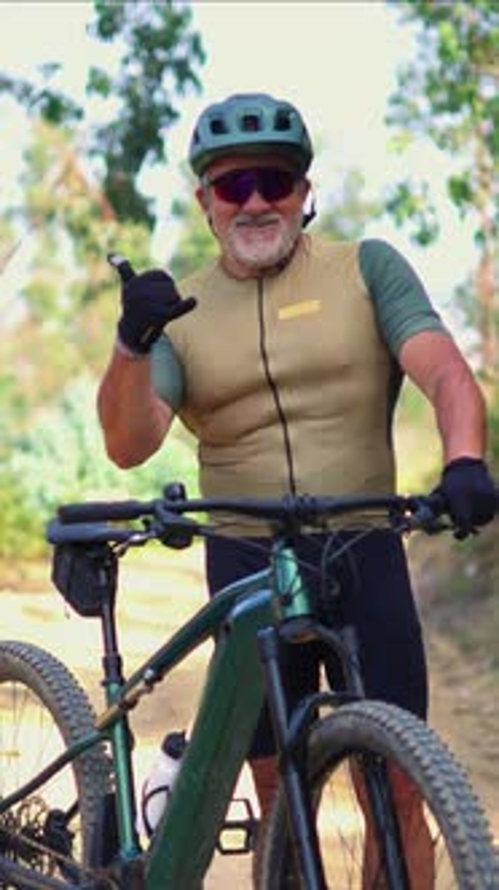 vertical Senior cyclist making the shaka sign on his e-bike, Sports
