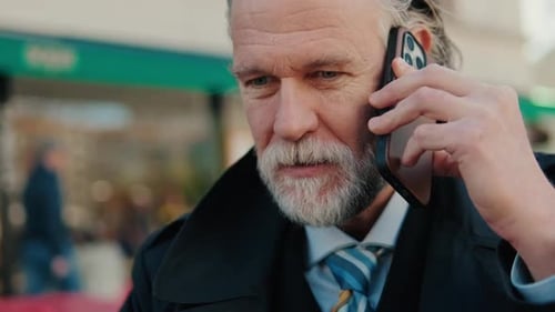 Mature Businessman Talking on Cell Phone in City