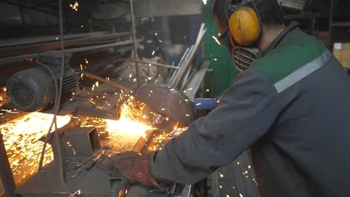 Worker Cutting Metal With Saw In Workplace