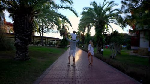 Family Walking Down Path with Palm Trees