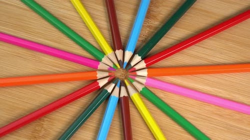 Colorful pencils rotate as sun rays background. Rainbow pencils for drawing. Assortment of colored