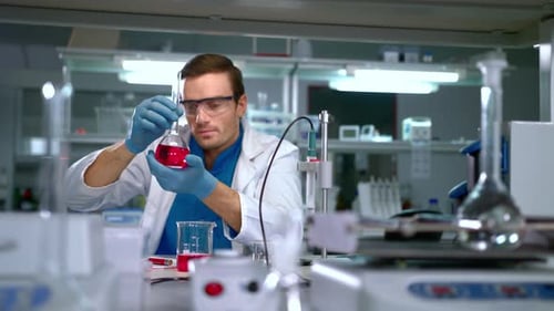 Chemiker untersucht Flüssigkeit in einer Glasflasche im Modern Lab. Suche nach Labormitarbeitern