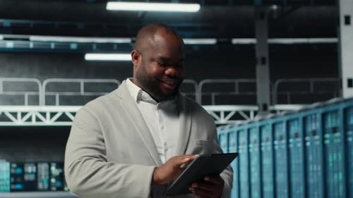 System Administrator Walking in Server Farm Deploying Infrastructure