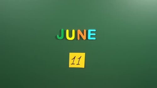 Hand sticking a sticker 11 June calendar day on school board. 11 date of June. Eleventh day June