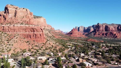 Ikonische amerikanische Stadt Sedona mit roten Wüstenbergen dahinter, Drohnenaufnahme aus der Luft
