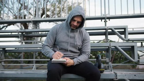 Adult Writes in Notebook After Workout Outdoors