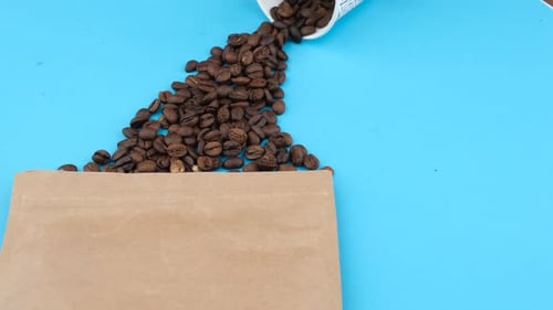 Coffee Beans Spill onto Blue Table with Paper Bag