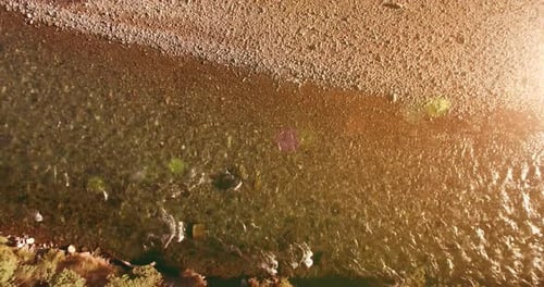Flug in geringer Höhe über einen frischen, schnellen Gebirgsfluss mit Felsen an einem sonnigen Sommermorgen