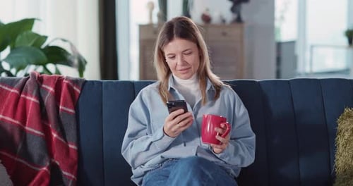 Woman Using Smartphone on Sofa at Home