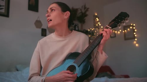 Woman Playing Guitar and Singing at Home