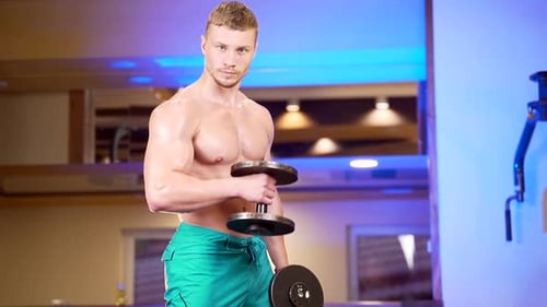 Muscular Man Lifts Dumbbell in Gym
