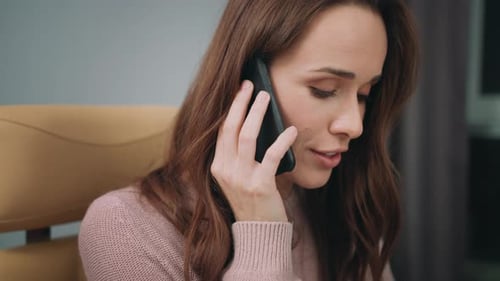 Woman in Pink Sweater Talking on Phone Indoors