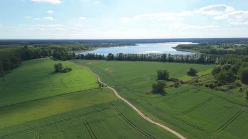 Eine wunderschöne Drohnenaufnahme einer malerischen Landschaft mit grünen Feldern, Wäldern, einem W