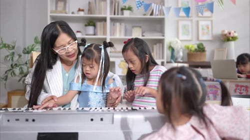 Teacher Helping Children Play Piano in Classroom