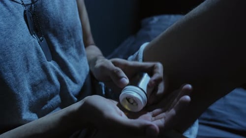 Hand Pours Medication Pills from Bottle at Night