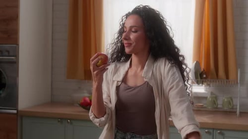 Woman Eats Fresh Apple in Kitchen