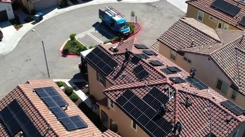 Solar Panel Installers At Work On Suburban Rooftop