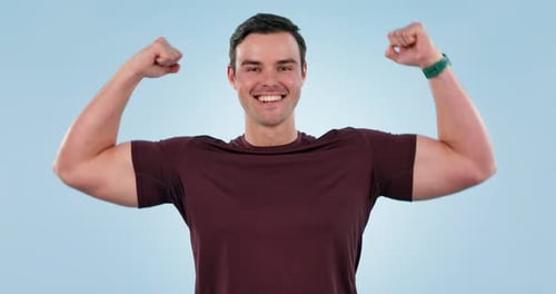 Smiling Man Flexing Biceps Against Blue Background