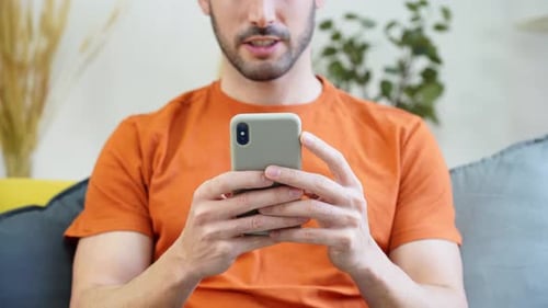 Man Uses Smartphone While Relaxing on Couch