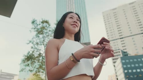 Woman Looking at Smartphone in Urban Setting
