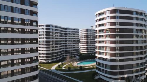 Drohnenaufnahme einer modernen Wohngebäudefassade mit braunen Paneelen und weißen Balkonen