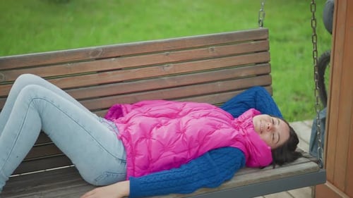 Woman Lounging on Bench with Bicycle Nearby in Tranquil Park Scene Individual Resting on Wooden