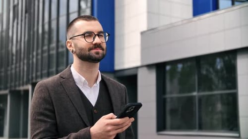 Man in Suit Using Smartphone Outside Office Building