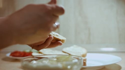 Woman Spreads Creamy Sauce on Bread in Kitchen