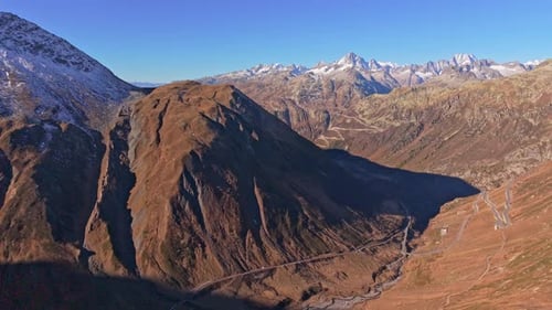 Winding Furka Pass under sunshine, Swiss Alps aerial shot.