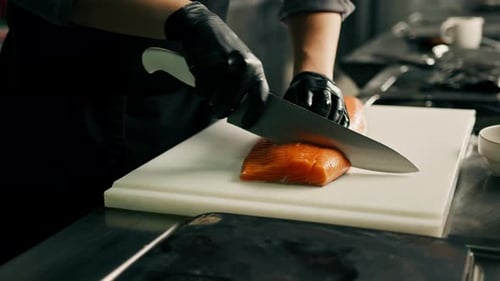 Professional kitchen in the hotel restaurant The chef cuts a large fresh salmon carcass with a knife