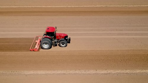 Tractor at work, prepares the field for planting seeds. Aerial view.