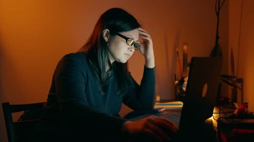 Woman Typing on Laptop at Desk at Night