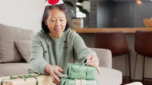 Senior Woman Unwrapping Christmas Gifts at Home