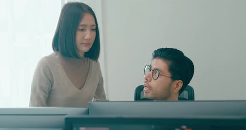 Two Colleagues Working Together at Computer in Office